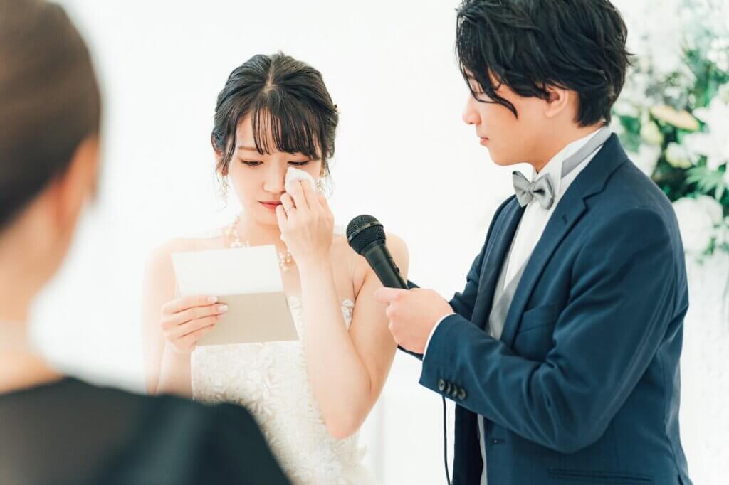 両親への感謝の気持ちをしたためた手紙を、涙ながらに読む新婦と、マイクを持ってサポートする新郎