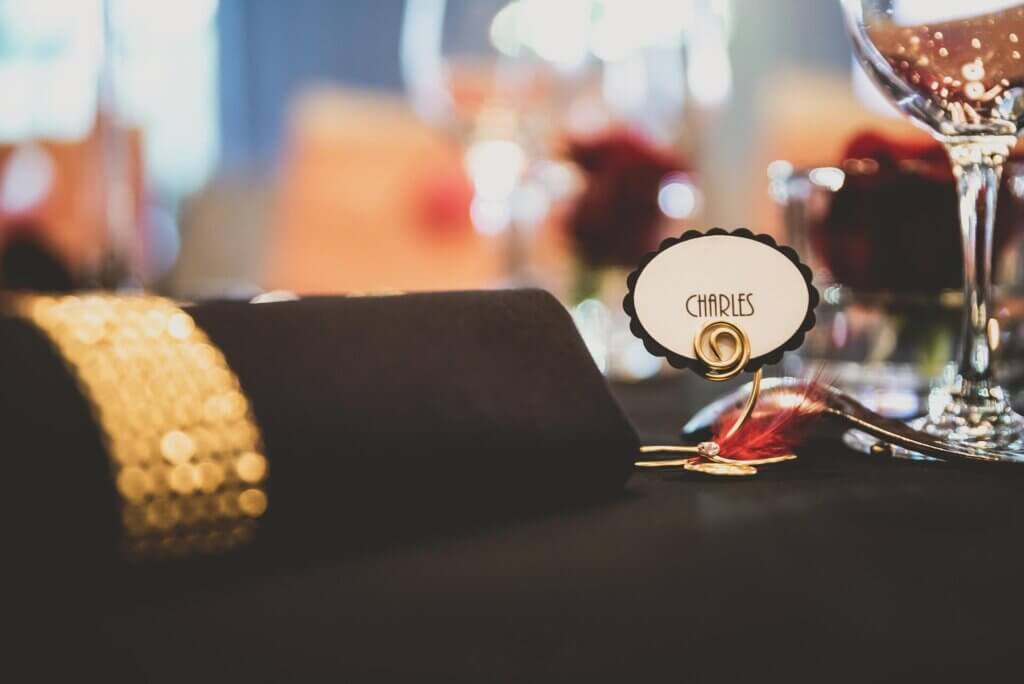 濃い茶色のテーブルクロスの上にCHARLESを書かれえたネームプレートが置かれているシックなテイストの結婚式のゲストテーブル