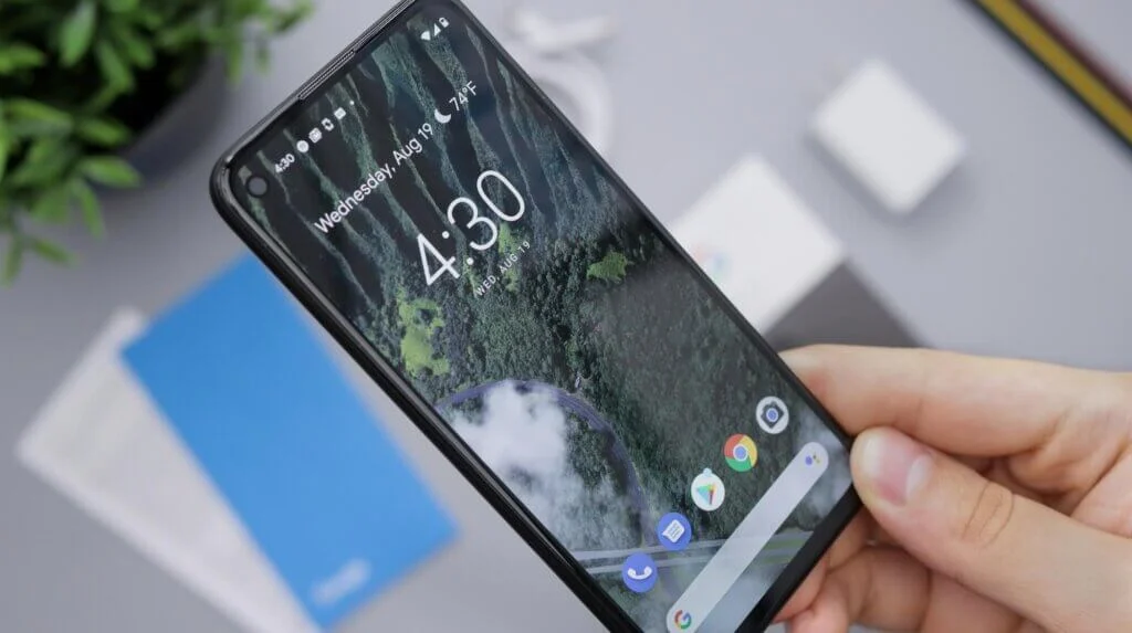 オフィスの机を背景に、スマートフォンを持っている