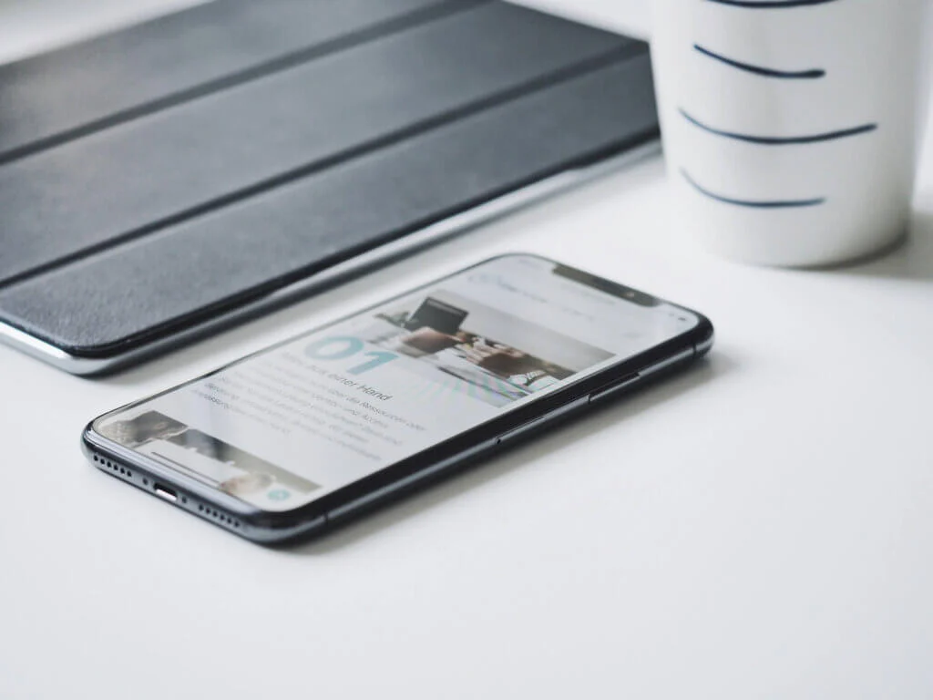 スマートフォンの横にタブレット端末とコーヒーカップが置かれている