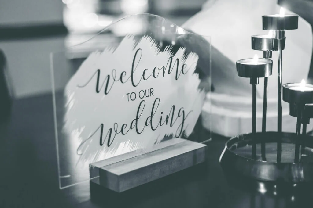 welcome to our weddingと書かれたガラスのオブジェと4つのキャンドルに火が灯っているモノクロの写真