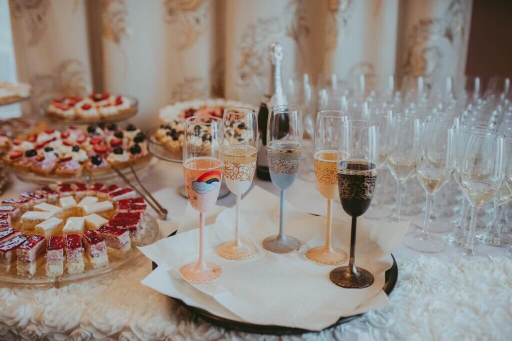 たくさんのシャンパンが注がれたグラスの前に、カップケーキやミニケーキ、デザートドリンクが置かれているデザートコーナー