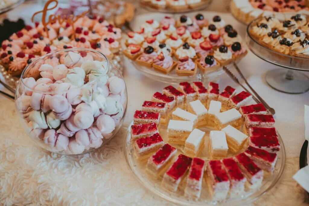 ピンクや茶色のカップケーキとイチゴソースがかかっているチーズケーキ、マカロンが盛り付けられているデザートコーナー