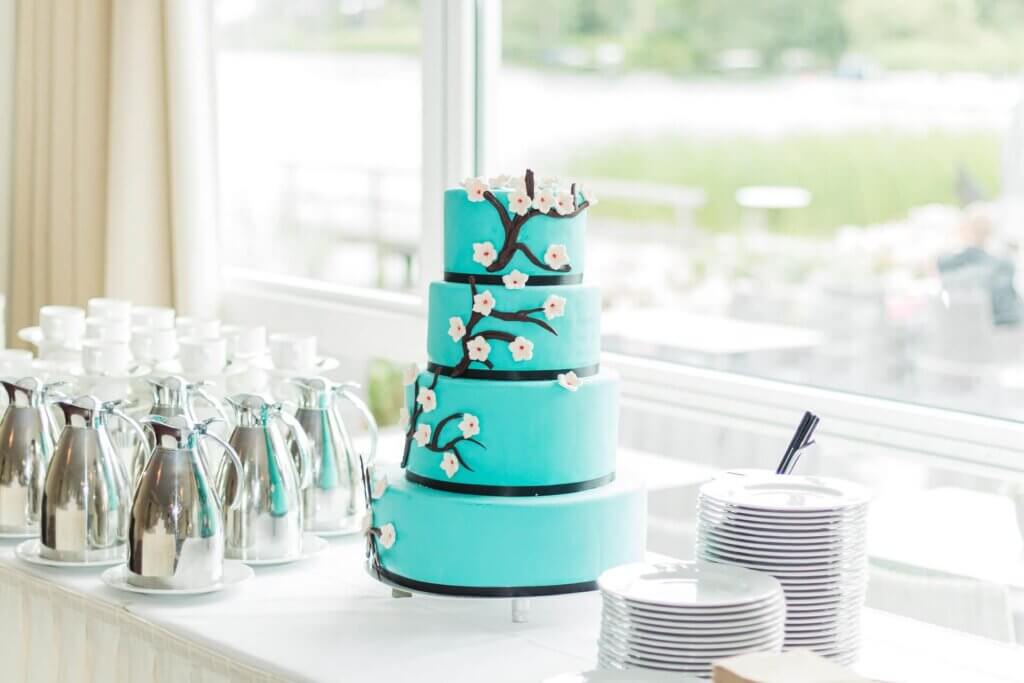 桜が咲いているデザインが施されているグリーンブルー色の4段ケーキ