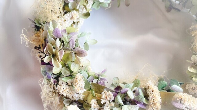 白と薄い紫の花、緑の葉でアレンジされているリースブーケ
