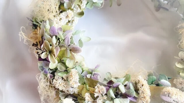 白と薄い紫の花、緑の葉でアレンジされているリースブーケ