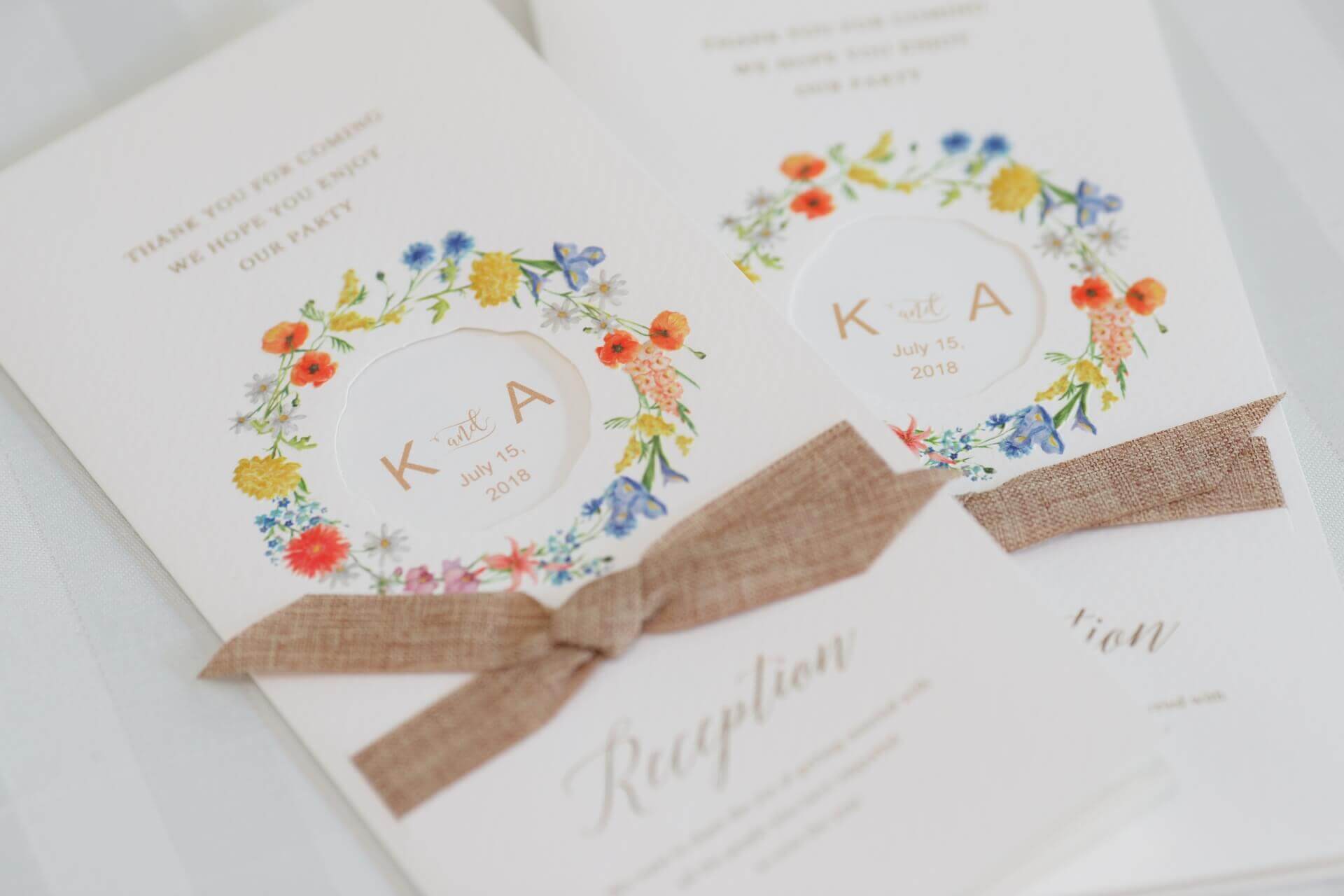 華やかな花のリースがデザインされた結婚式の席次表。茶色の麻リボンがアクセントになったナチュラルなデザイン。