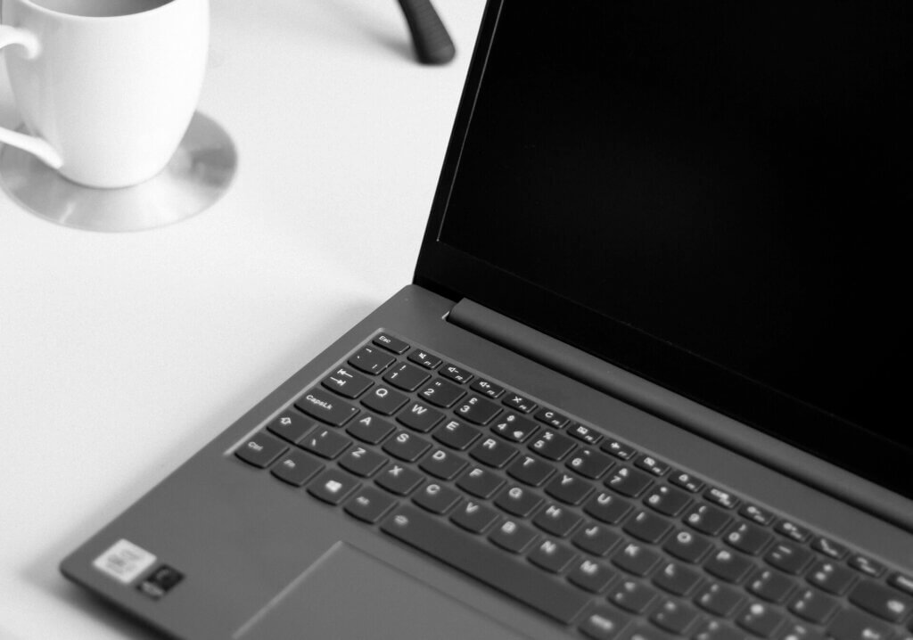 デスクの上のノートパソコンと白いマグカップ。席次表を自宅で手作り・デザインしている様子。