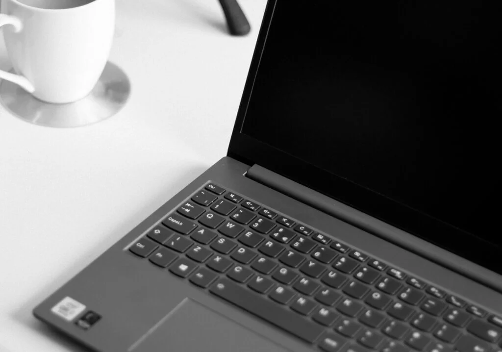 デスクの上のノートパソコンと白いマグカップ。席次表を自宅で手作り・デザインしている様子。