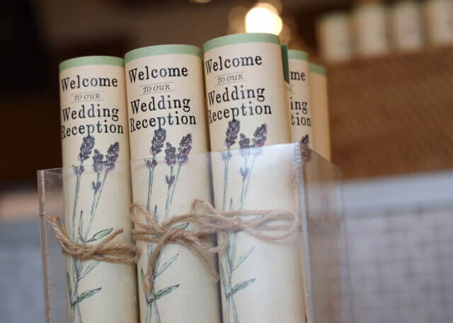 ラベンダーのイラストが描かれ、麻紐で結ばれたロールタイプの席次表。クリアケースに並べられた様子。