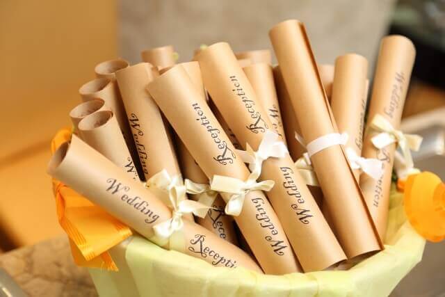 クラフト紙を丸めて白いリボンで結んだロールタイプの席次表が、カゴいっぱいに詰められた様子。