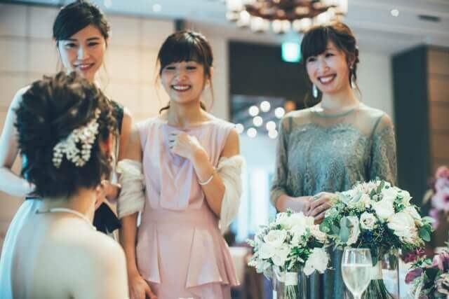 結婚披露宴にて、新婦のテーブル(高砂)を訪れ、笑顔で祝福の言葉をかけるドレス姿の女性ゲストたち