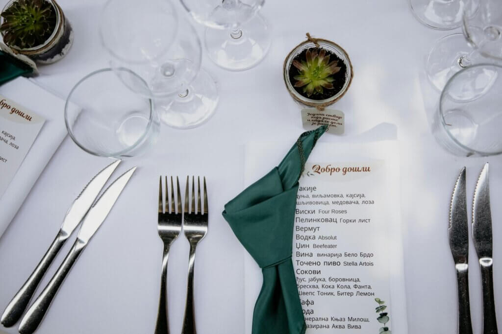 深緑のナプキンが添えられた結婚式のメニューカードと多肉植物の席札。上から見たテーブルコーディネート。