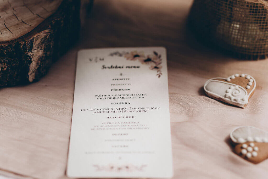 切り株やハート型のアイシングクッキーを添えた、花柄があしらわれた温かみのある婚礼用メニュー表。