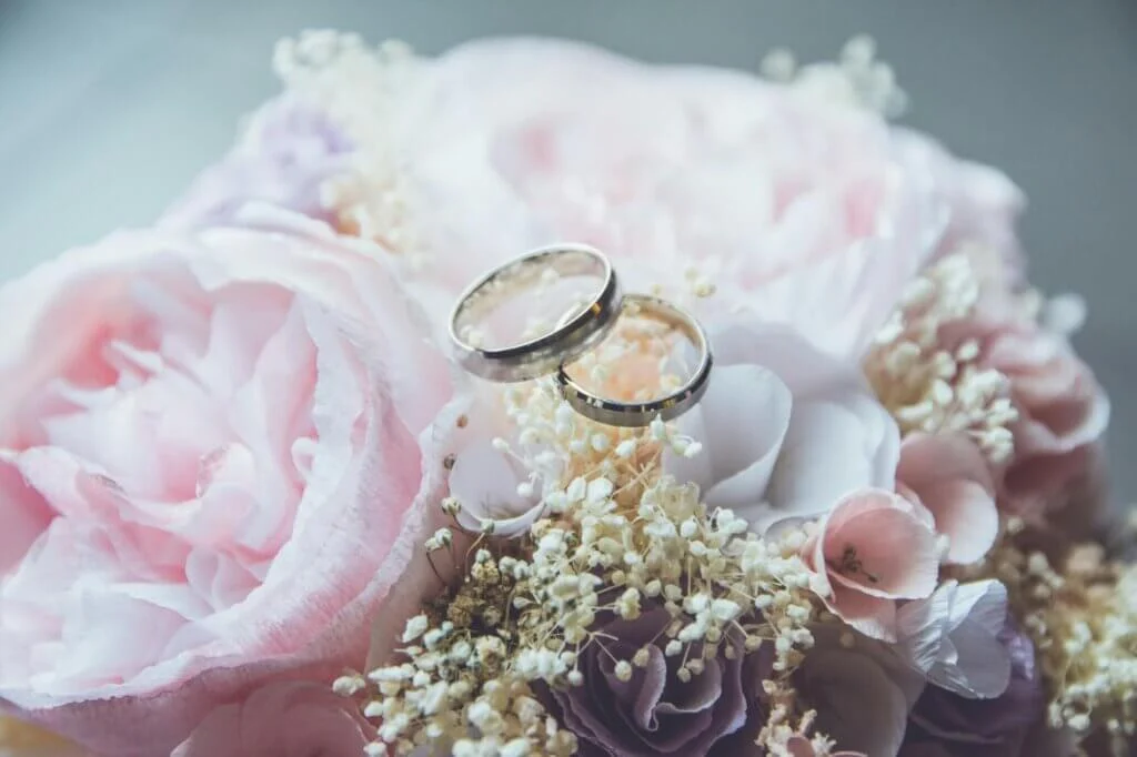 淡いピンクのウェディングブーケの上に置かれた、お揃いの結婚指輪ふたつ