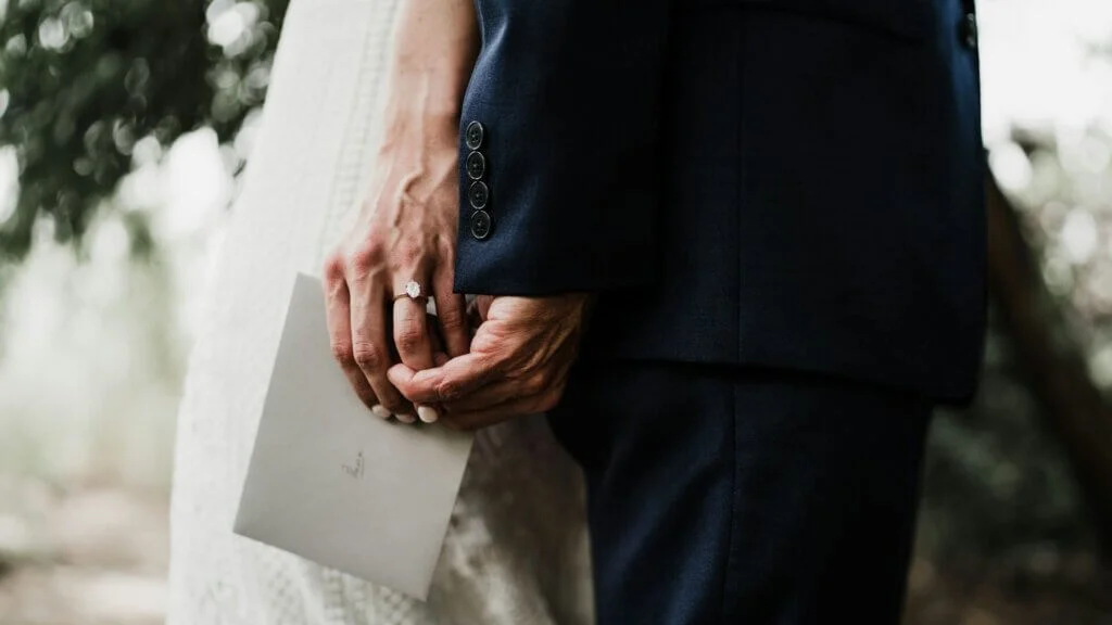 新郎の手を握り、手紙を渡そうとする新婦。薬指には結婚指輪が光る。