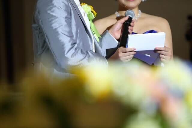 披露宴の最後に新婦から両親への手紙を読み、新郎がそっと新婦の口元にマイクをアテンドしている。