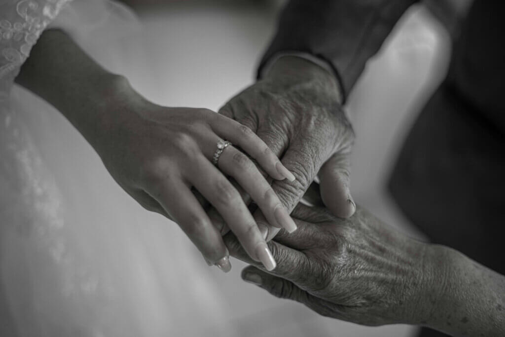 年老いた祖父母の手の上に、新婦の手が重ねられている。その薬指には、結婚指輪が光っている。