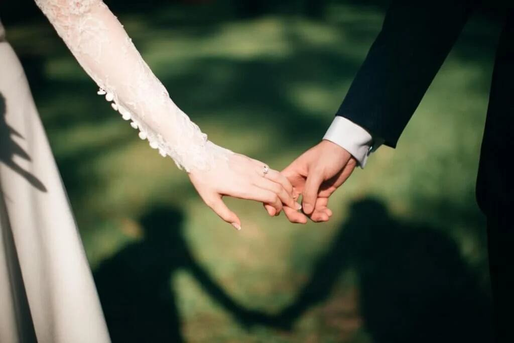緑いっぱいの森の中で手をつなぐ新郎新婦の手元