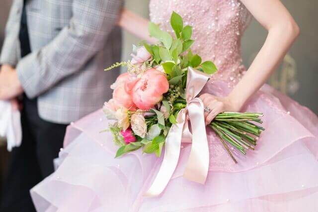 ピンクドレスの花嫁がコーラルピンクのブーケを持つ