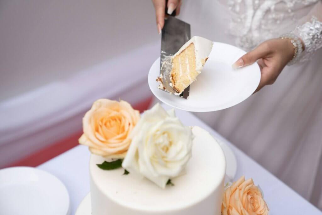 ウェディングケーキにバラを飾り、花嫁がケーキをサーブする場面