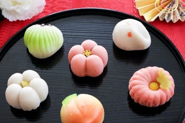 黒い盆に並んだ色とりどりの上生菓子、和菓子ビュッフェのイメージ