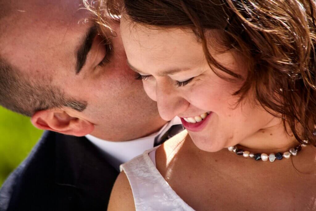 誓いのキスの代わりに額や頬を寄せ合い微笑む新郎新婦のアップ