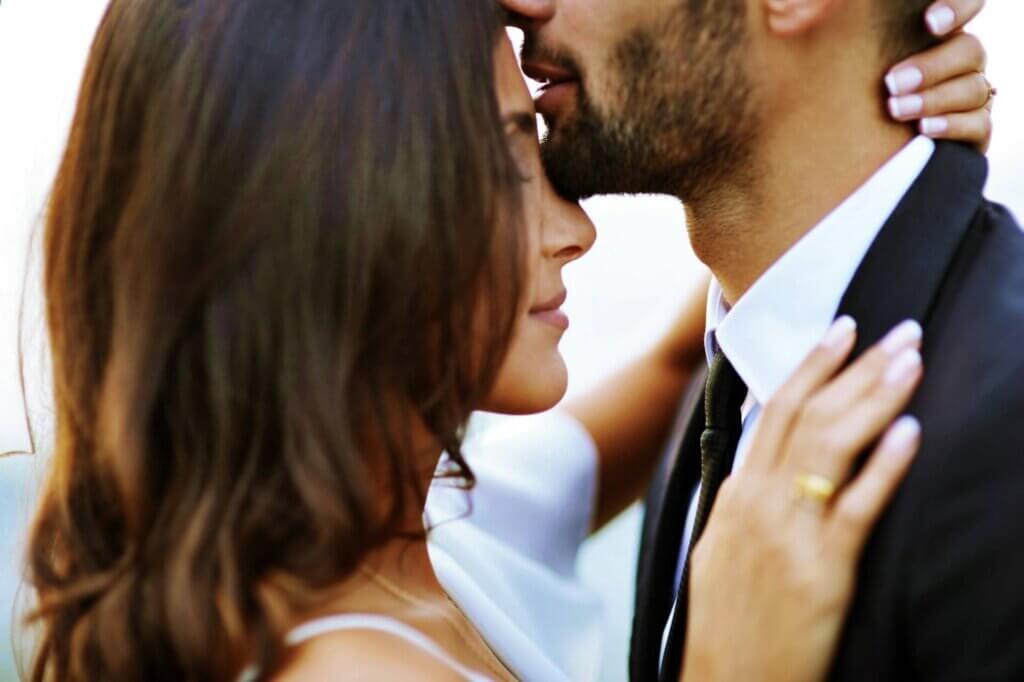 新婦の額に優しくキスをする新郎のアップ、愛情が伝わる結婚式の瞬間