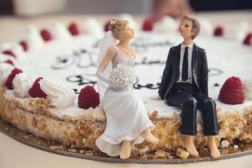 ラズベリーとクリームがたっぷり飾られたケーキの上に、仲良く座る新郎新婦の人形が乗ったデザイン。