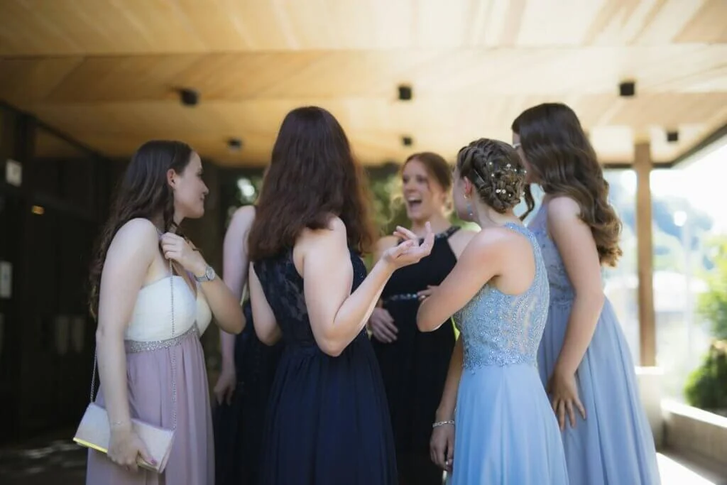 結婚式でドレスを着た友人同士が明るい屋外で楽しそうに会話している様子