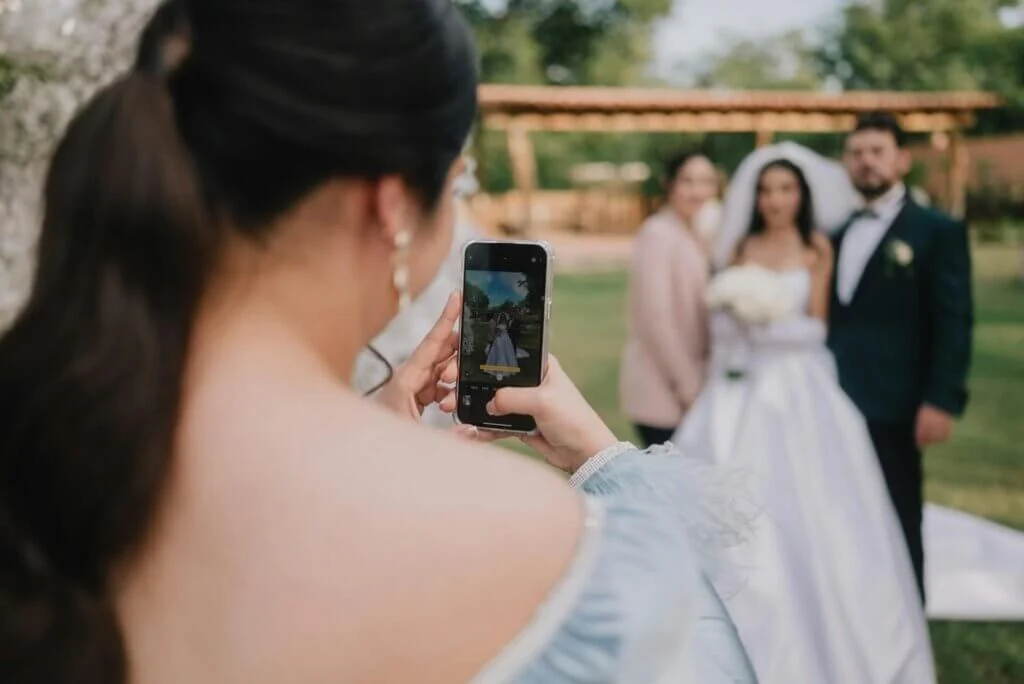 ゲストがスマートフォンを向け、美しく佇む新郎新婦の姿を嬉しそうに撮影する様子