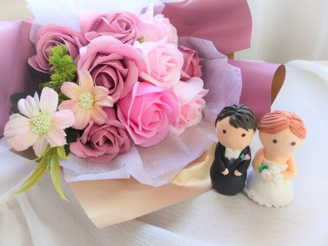 両親への贈り物にする花束と新郎新婦をかたどった人形