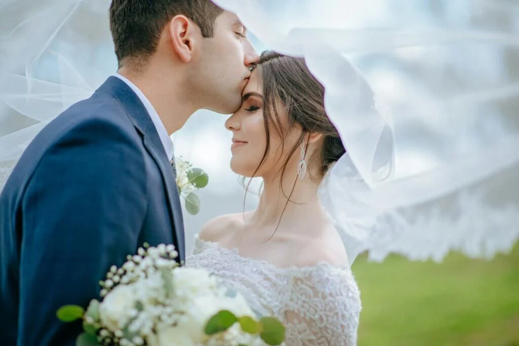 ベールを背景に新婦の額へキスをする新郎と誓いのキスのアレンジ例