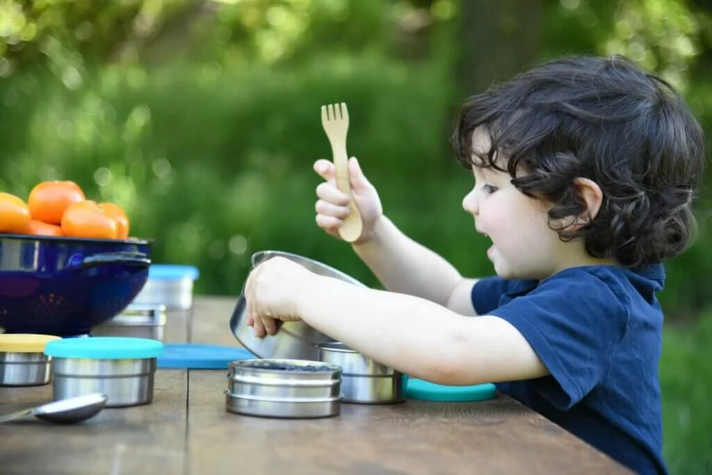 木のフォークを手に容器のふたを開ける男の子