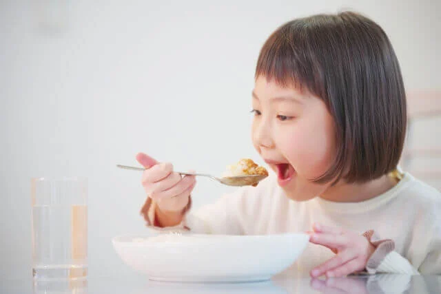 スプーンで料理を口に運ぶ女の子